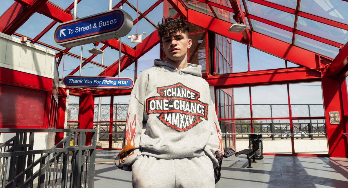One Chance campaign: model wearing a gray graphic hoodie at a red-framed Cleveland transit station.