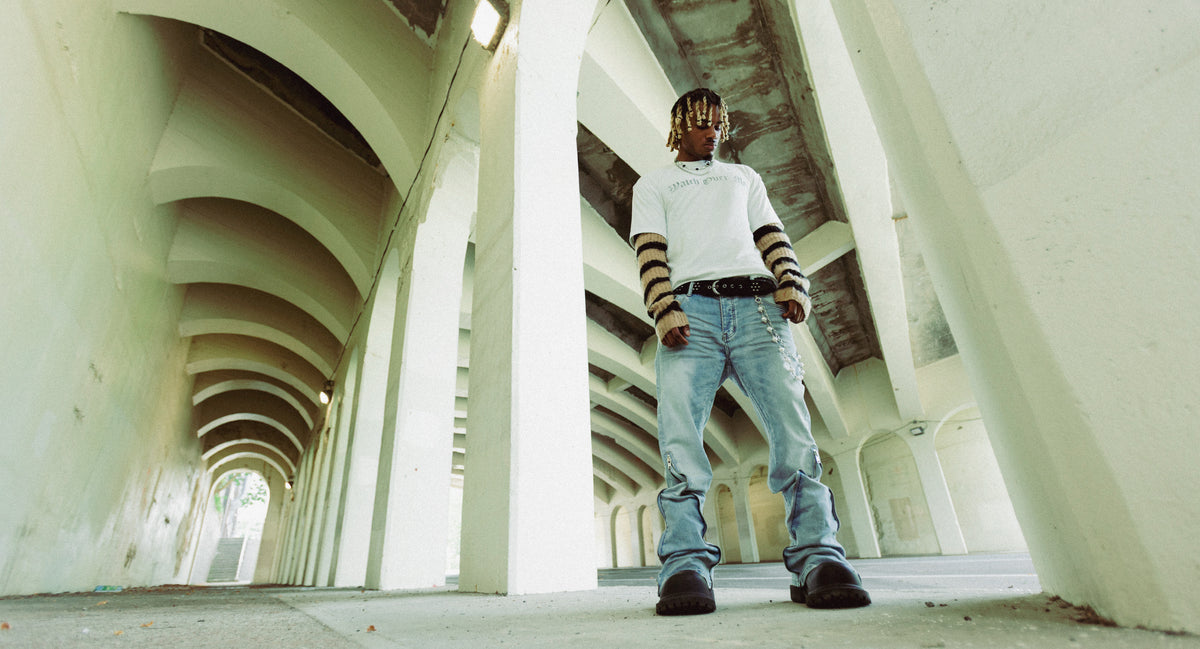 PRVT LBL campaign: model wearing layered sleeves and washed denim beneath a concrete colonnade.