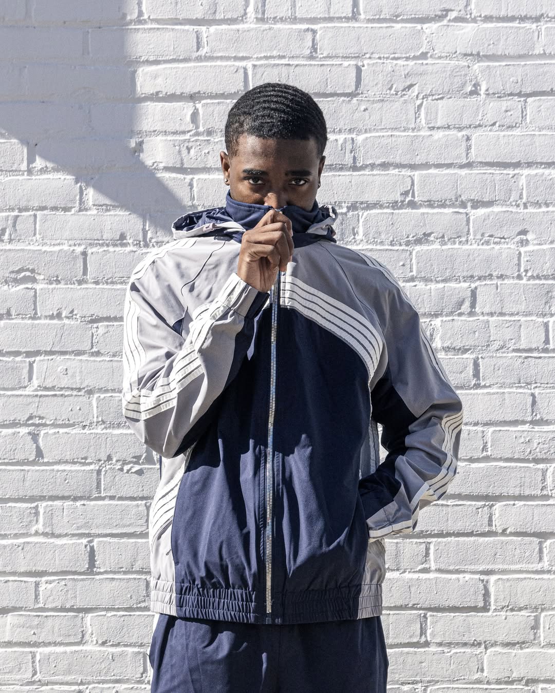 Jordan Craig GT tracksuit photographed against a white brick wall